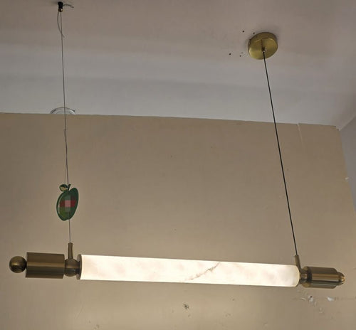 Light fixture hanging from a ceiling with a plain wall background