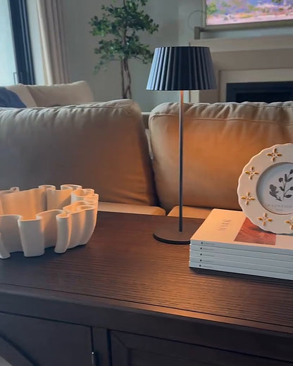 Black ribbed cordless table lamp on a living room console table